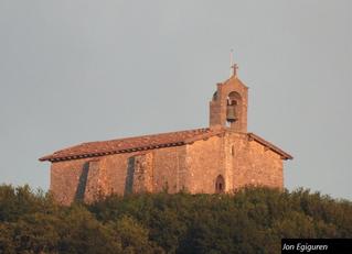Ilunabarreko eguzkiaren azken izpien kolore bereziekin  ikusten da ermita Aizarnatik. Edozein aldetik begiratuta ere beti polita ikusten da ermita zahar hau.  Aizarnatik aterata dago argazkia 